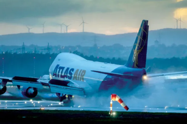 طائرة تهبط في المطار الدولي مع توربينات رياح في الخلفية في فرانكفورت، ألمانيا (أ.ب)