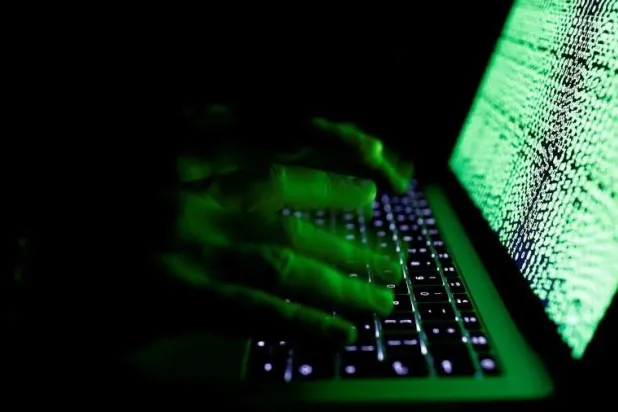 رجل يكتب على لوحة مفاتيح الكمبيوتر أمام الرمز الإلكتروني المعروض في هذه الصورة التوضيحية التي تم التقاطها في 1 مارس 2017 (رويترز)