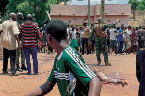 رجل يشتبه في مشاركته بهجوم «إرهابي» تم إحباطه يرقد بلا حراك على الأرض بعد تعرضه للضرب من قبل حشد أمام قاعدة عسكرية في كاتي بمالي يوليو الماضي (أ.ف.ب)