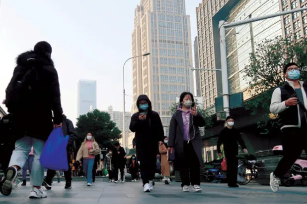 صينيون في أحد الشوارع التي عادت للازدحام بعد تخفيف السلطات القيود الصحية (رويترز)
