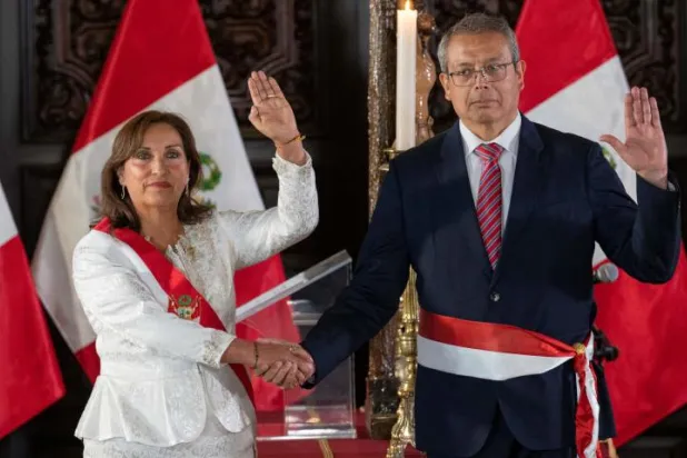 رئيسة بيرو دينا بولوارت تصافح بيدرو أنغولو  رئيس الحكومة الجديد بعد أداء اليمين الدستورية في قصر الحكومة في ليما (أ.ف.ب)