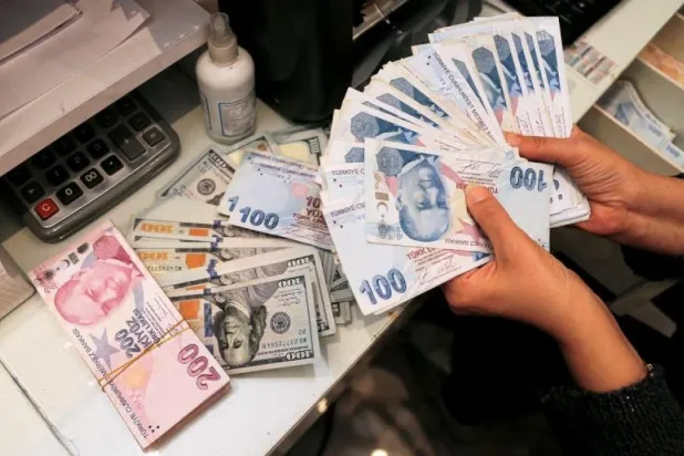 صراف يحمل أوراقاً نقدية من الليرة التركية في مركز للصيرفة في 12 أكتوبر 2021 (رويترز)
