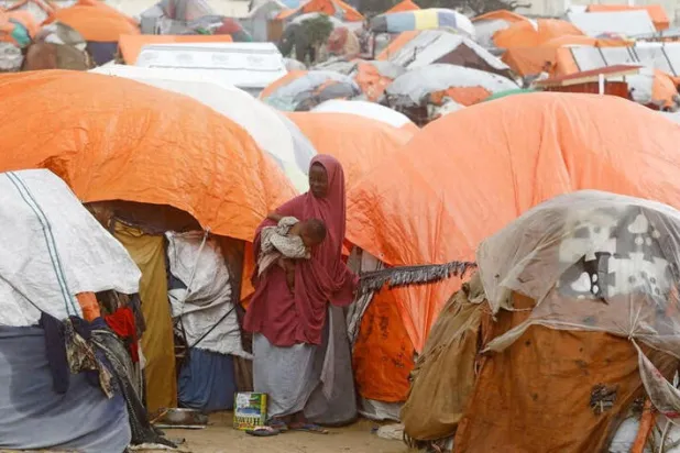 إمرأة صومالية تقف خارج مأواها في مخيم علاء فوتو للنازحين في ضواحي مقديشو (رويترز)