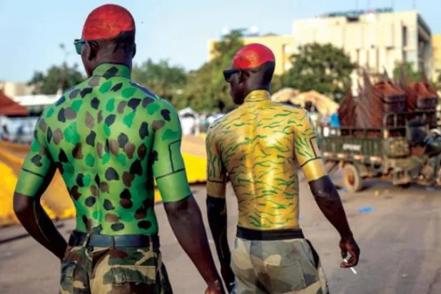 رجال يرتدون رسماً عسكرياً على أجسادهم يمشون خلال تجمع لإظهار الدعم للجيش في واغادوغو (أ.ف.ب)