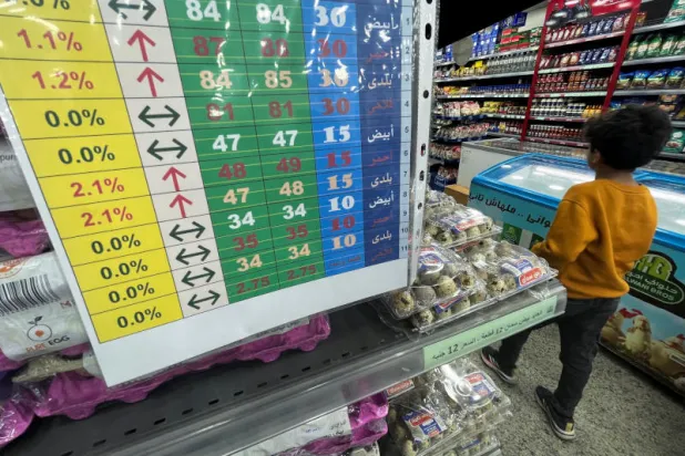 صبي يمر قرب قائمة تعرض أسعار البيض المتغيرة في متجر مصري (رويترز)