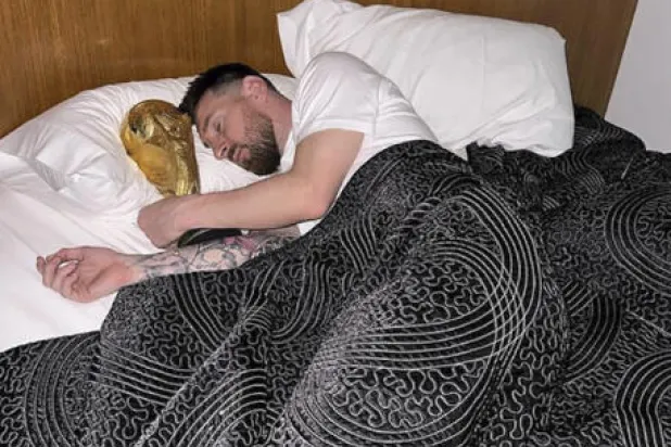 ميسي نشر ثلاث صور له وهو يحتضن الكأس على سريره في غرفته (أ.ف.ب)