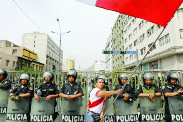 بيروفية تلوح بعلم خلال احتجاج ضد قرار البرلمان عزل الرئيس السابق بيدرو كاستيّو، في 7 ديسمبر الحالي (رويترز)