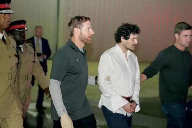 سام بانكمان-فرايد يسير مكبلاً في الطريق إلى ترحيله للولايات المتحدة الأميركية من جزر الباهاماس (رويترز)