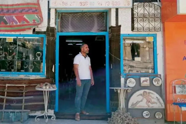 تونسي أمام متجر لبيع التذكارات في إحدى المناطق السياحية بتونس (رويترز)