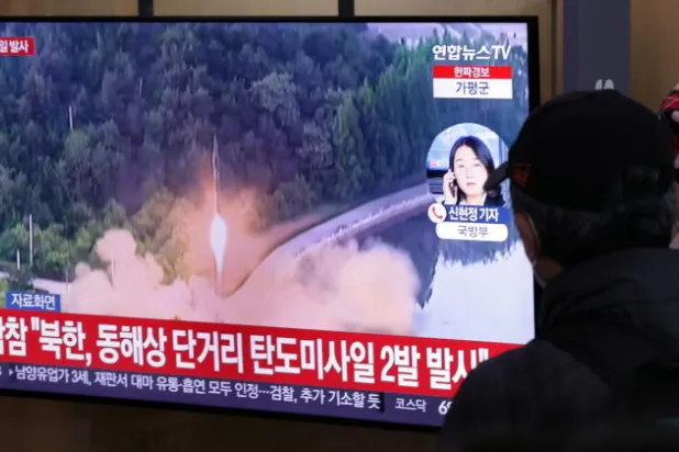 أشخاص يشاهدون عبر التلفاز تقريراً حول إطلاق كوريا الشمالية لصاروخين باليستيين قصيري المدى (إ.ب.أ)