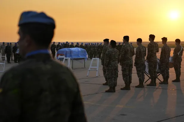 Lebanese soldiers, Irish and other nationalities U.N. peacekeepers, stand around the coffin draped by the United Nations flag of their comrade Pvt. Seán Rooney who was killed during a confrontation with residents near the southern town of Al-Aqbiya on December 14, during his memorial procession at the Lebanese army airbase, at Beirut airport, Sunday, Dec. 18, 2022. (AP)