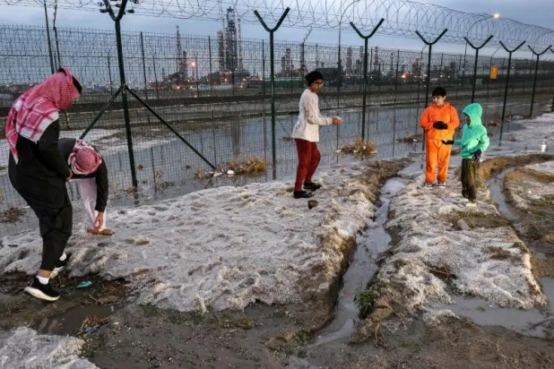 شباب يحملون الثلوج في الكويت (أ.ف.ب)