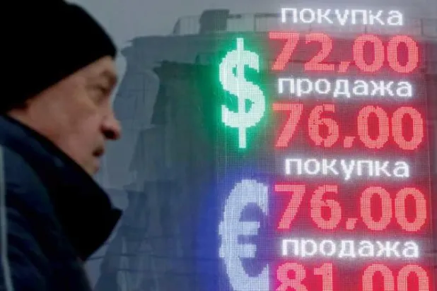 رجل يمر أمام شاشة تعرض سعر الروبل الروسي مقابل العملات الأجنبية في العاصمة موسكو (إ.ب.أ)
