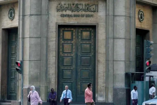 أناس يمشون أمام مقر البنك المركزي المصري بوسط القاهرة، مصر (رويترز)