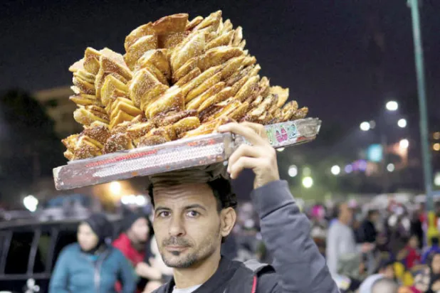 بائع معجنات في سوق شعبية يعرض بضاعته خلال الاحتفال بمولد السيدة نفيسة في مصر (رويترز)