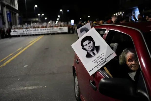 Maria Bellizzi, 1977'de gözaltına alındıktan sonra kaybedilen oğlu Humberto'nun fotoğrafıyla Sessizlik Yürüyüşü'ne katıldı (Reuters)