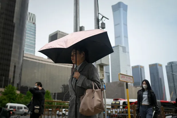 مارة في أحد شوارع بكين الرئيسية (أ.ف.ب)