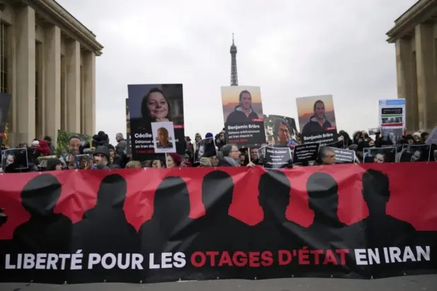 Göstericiler, geçen Ocak ayının sonunda Paris’te düzenlenen bir gösteri sırasında İran tarafından gözaltına alınan Benjamin Briere ve diğer Fransızların fotoğrafını taşıyor (AP)