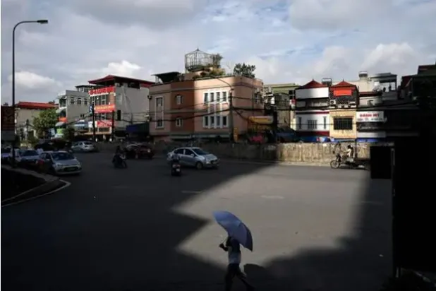 رجل يحمل مظلة للحماية من الشمس بشارع في هانوي (أرشيفية - أ.ف.ب)