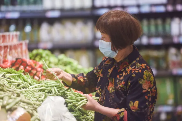 سيدة صينية تشتري الخضراوات من أحد متاجر البقالة في هوانغزو شرق الصين (أ.ف.ب)