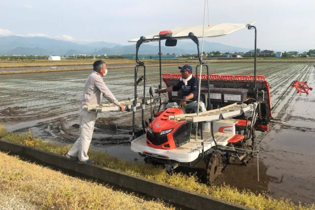 مزارعان يتحدثان خلال إعداد حقول للأرز في مدينة ياماغتا شمال اليابان (رويترز)