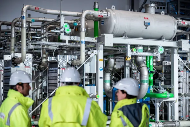 ثلاثة مهندسين أمام وحدة إنتاج الهيدروجين الأخضر في أحد المشروعات الألمانية (إ.ب.أ)