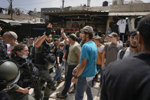 ضباط الشرطة الإسرائيلية يفصلون بين الإسرائيليين والفلسطينيين أمام باب العامود في القدس (أ.ب)