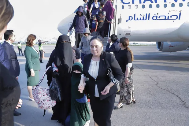 هبوط مواطنين طاجيك من طائرة في مطار دوشاندي الأحد بعد إجلائهم من مخيمات في الحسكة (أ.ف.ب)