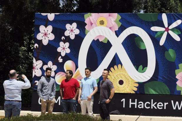 أشخاص يلتقطون الصور أمام شعار «ميتا» بالمقر الرئيسي في كاليفورنيا بالولايات المتحدة الأميركية (إ.ب.أ)