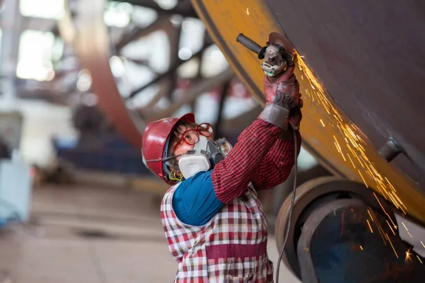 عامل يلحم أجزاء من مواد البناء في مصنع في نانتونغ بمقاطعة جيانغسو شرق الصين (أ.ف.ب)