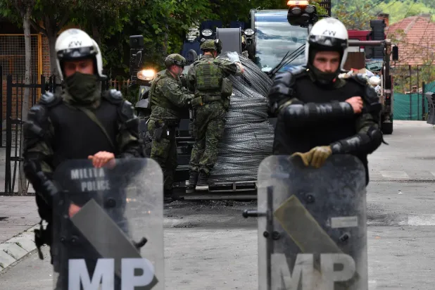 جنود من قوات حفظ السلام التابعة للناتو أمام سياج من الأسلاك الشائكة أمام مبنى البلدية في زفيكان بكوسوفو (إ.ب.أ)