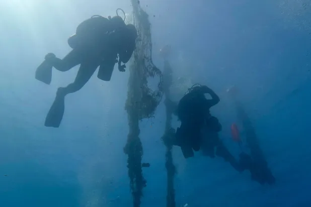 غواصون متطوعون من منظمة «إيجيان ريبيرث» اليونانية خلال حملة تنظيف لقاع بحر إيجه قبالة جزيرة سانتوريني اليونانية في 3 يونيو 2023 يستعيدون شباك صيد متروكة (أ.ف.ب)