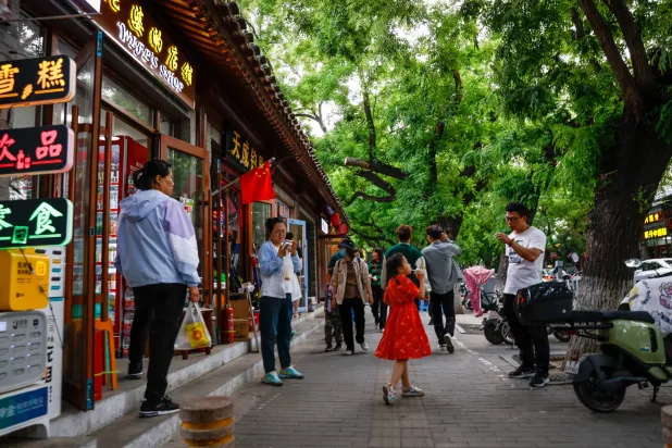 أشخاص يسيرون بجانب المتاجر في بكين - الصين (إ.ب.أ)