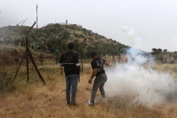 متظاهر لبناني يعيد إلقاء عبوة غاز مسيل للدموع عبر الحدود باتجاه جنود إسرائيليين خلال مظاهرة اليوم في 9 يونيو 2023 بالقرب من الخط الأزرق قرب بلدة كفرشوبا اللبنانية (أ.ف.ب)