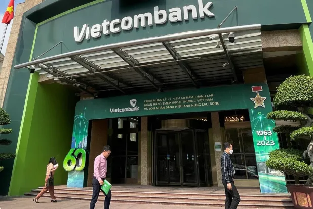 أشخاص يمشون أمام مقر بنك فيتنام في العاصمة هانوي فيتنام (رويترز)