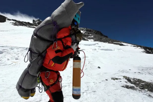 نجيما تاشي يمشي وهو يحمل متسلقاً ماليزياً أثناء إنقاذه من منطقة الموت فوق المعسكر الرابع في إيفرست (رويترز)