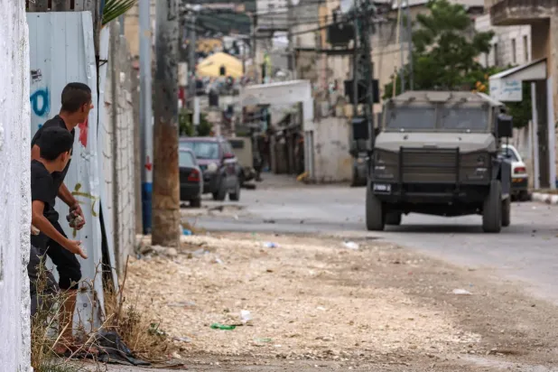 İsrail’in bugün Nablus’un eteklerindeki Balata mülteci kampına düzenlediği baskında Filistinli gençler İsrail ordusuna ait araçlara taş atıyor (AFP)
