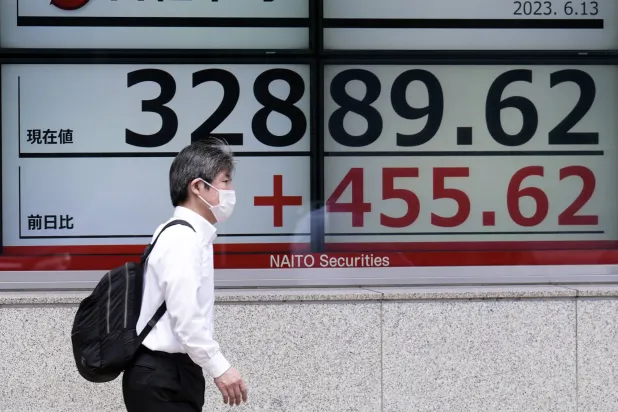 شخص يمشي أمام لوحة أسهم إلكترونية تعرض مؤشري نيكي الياباني وداو الأميركي... ارتفع المؤشر نيكي الياباني يوم الثلاثاء ليغلق فوق مستوى 33 ألف نقطة للمرة الأولى منذ 33 عاماً في طوكيو، اليابان - (أ.ب)