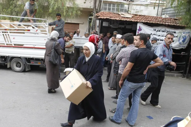 Suriyeliler Şam'daki Dünya Gıda Programı (WFP) merkezi önünde yardım almak için sıraya giriyor (Reuters - Arşiv)