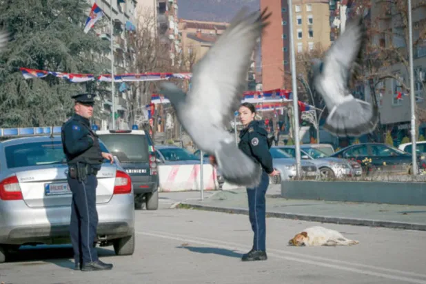 شرطيان من كوسوفو يحرسان جسراً يفصل بين الجنوب الصربي والشمال الألباني في ميتروفيتشا (أ.ب)
