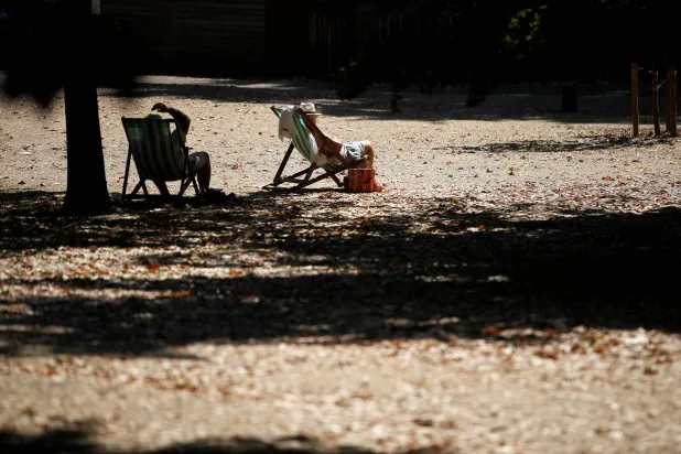 بريطانيون يجلسون في الشمس خلال موجة من الطقس الحار والجاف في لندن، العام الماضي (رويترز)