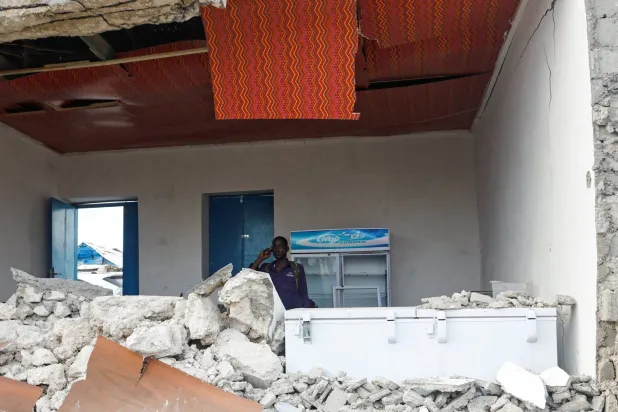 ضابط صومالي يستخدم هاتفه داخل أنقاض مطعم «بيرل بيتش» بعد هجوم شنته حركة «الشباب» على شاطئ ليدو في مقديشو في 10 يونيو (رويترز)