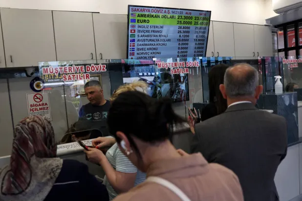 أشخاص يصطفون في طابور ببورصة العملات بأنقرة (أ.ف.ب)