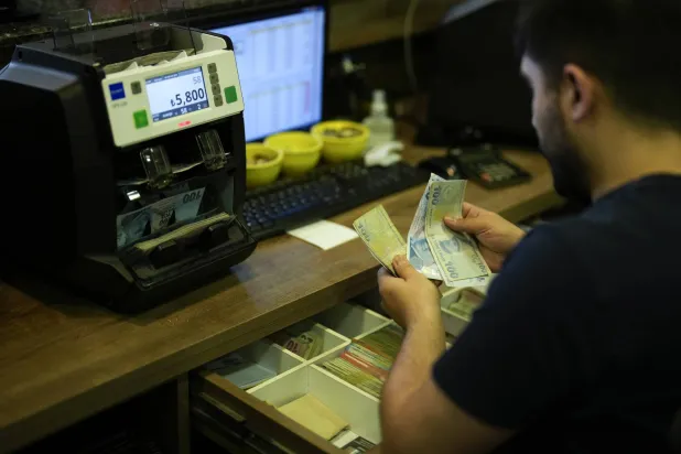 موظف يقوم بعد أوراق نقدية في أحد محلات الصرافة بمدينة إسطنبول التركية قبل قرار البنك المركزي رفع الفائدة إلى 15% (أ.ب)