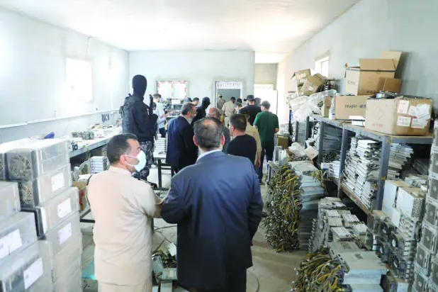 عدد من المسؤولين يعاينون المعدات الحجوزة المستخدمة في عملية «تعدين العملات المشفرة» (مكتب النائب العام)