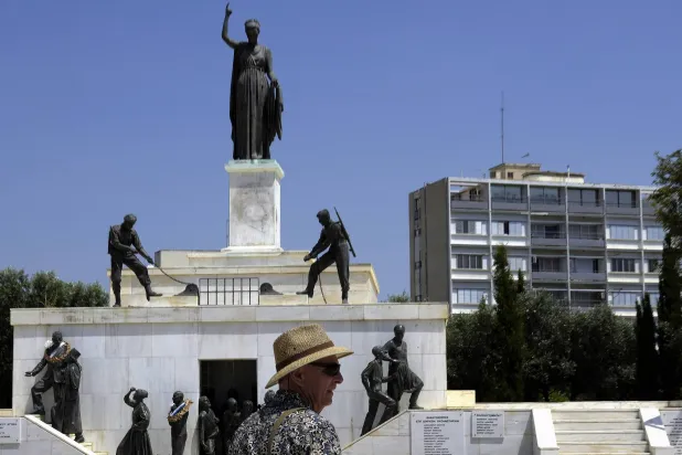سائح يقف أمام تمثال لجندي في نصب الحرية في وسط العاصمة نيقوسيا في 16 يونيو الحالي (أ.ب)