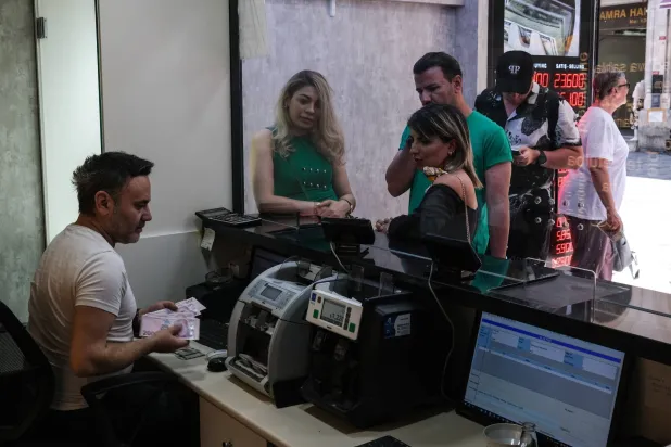 سائحون يبدلون الأموال في مكتب صرافة بإسطنبول (إ.ب.أ)