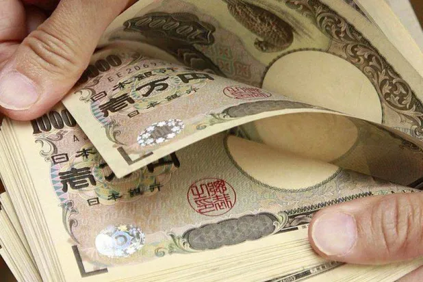 رجل يعد أوراقاً نقدية من فئة الين الياباني (أ.ف.ب)