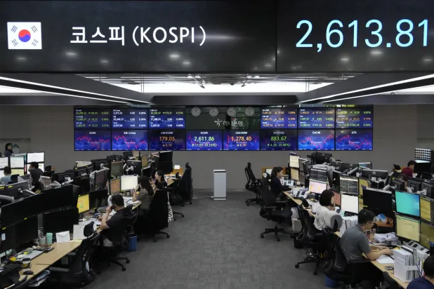 موظفون يتابعون مؤشر أسعار أسهم الشركات الكورية المركب (KOSPI) في غرفة تداول بسيول (أ.ب)