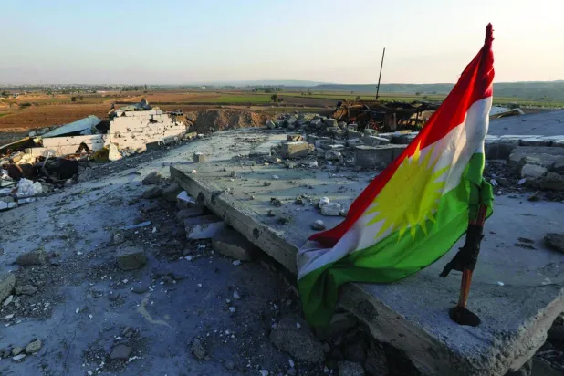 Kuzey Irak’ta, Kerkük’ün kuzeyindeki Bardi kasabasındaki bir binanın üzerine asılan Kürt bayrağı. (AFP)